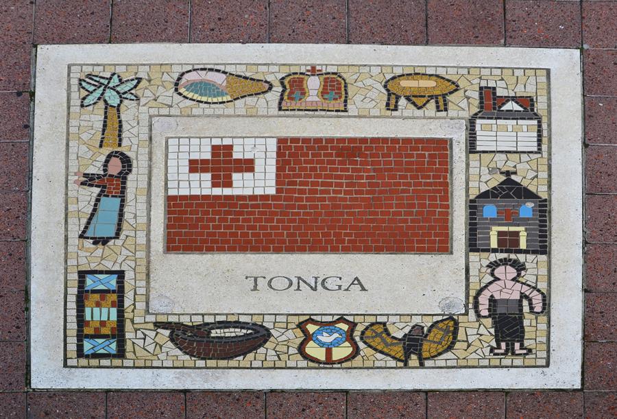 This tile at the Millenium Stadium in Cardiff, UK was created when Tonga participated in the 1999 Rugby World Cup. Rugby is important in Tonga (bottom row middle = emblem of the Tongan rugby team), as is the King (middle top row), the church (middle right), Kava (preparation bowl top and serving bowl bottom row), declicately woven mats (bottom left) and coconut trees. Also depicted are flying foxes (bottom right), a triton shell traditionally used instead of horns (top left) and a school to show the importance of education (top right).